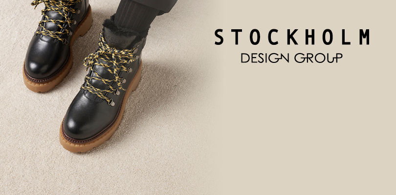 Svarte lærstøvler med gule og svarte lisser og brun såle fra Stockholm Design Group på lys bakgrunn.