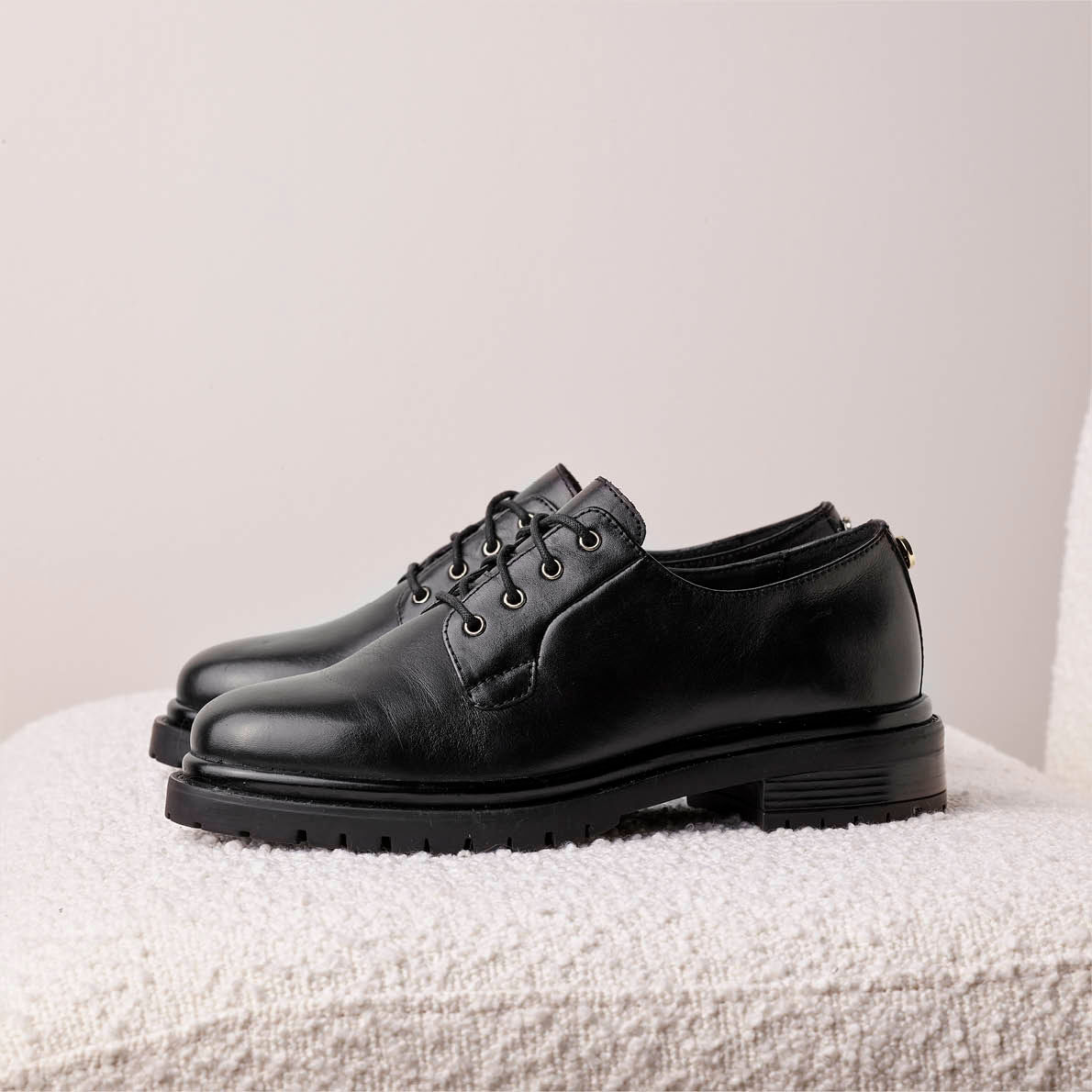 sorte lace ups fra siden på pusete stol