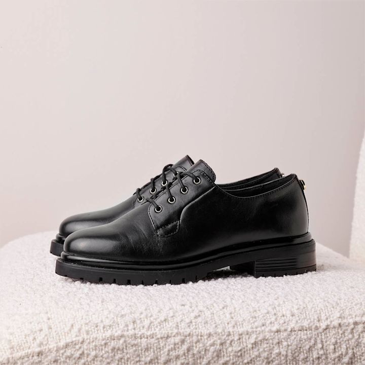 sorte lace ups fra siden på pusete stol