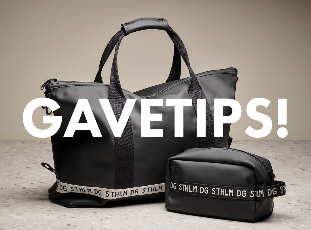 Svart weekendbag og toalettmappe med "STHLM DG"-logo og teksten "GAVETIPS!" i hvitt over bildet.