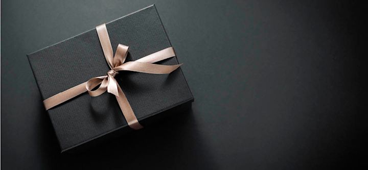 sort gaveeske med gyldenst bånd, på sort bakgrunn