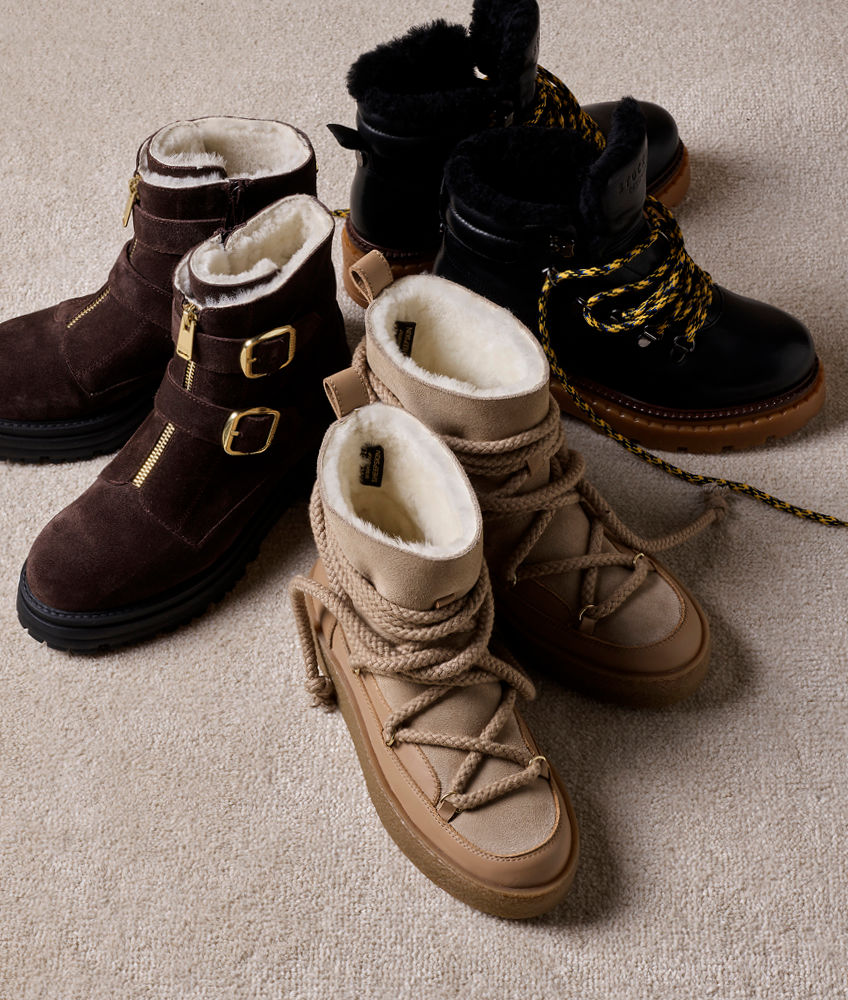 Tre par vinterstøvler med pelsfôr: brune med spenner, beige med snøring og svarte med gule lisser på beige teppe.