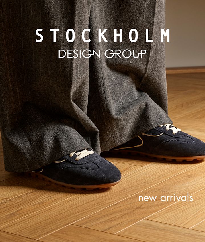 Mørkeblå semsket sneakers med beige snørebånd og brun såle, stylet med vide grå bukser på tregulv.