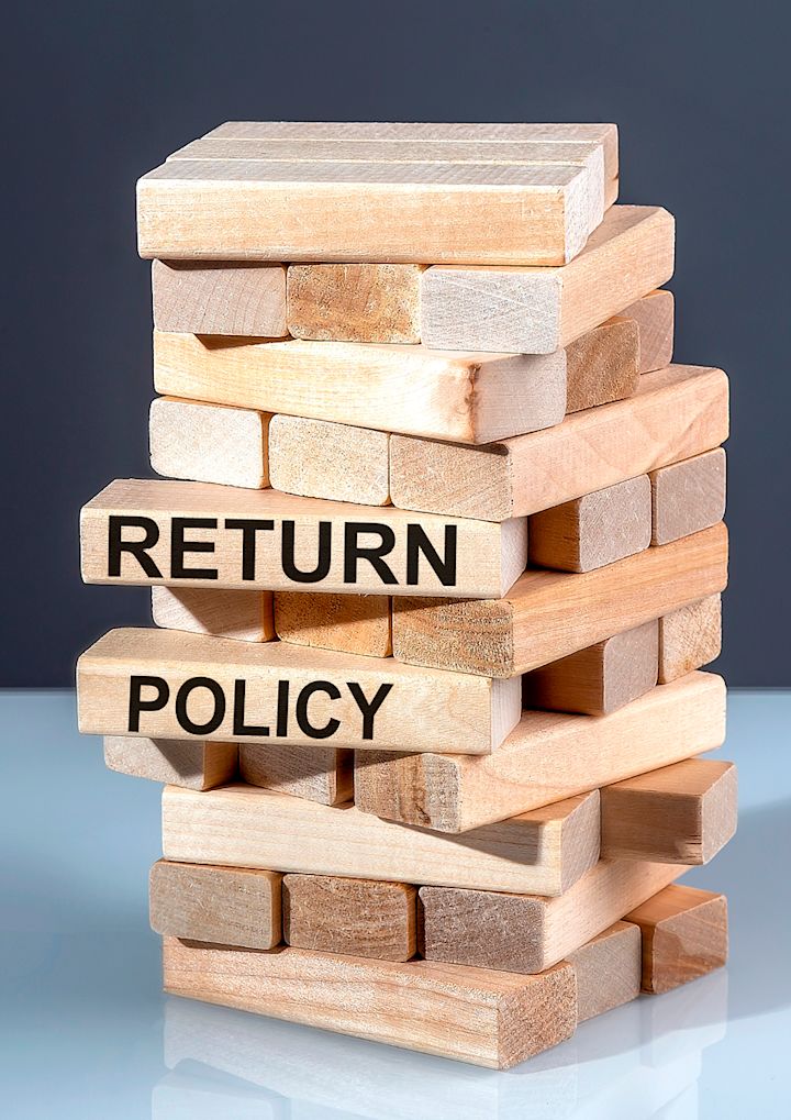 Stable tårn av treklosser med to klosser merket "RETURN POLICY" som stikker ut, mot en mørk bakgrunn.