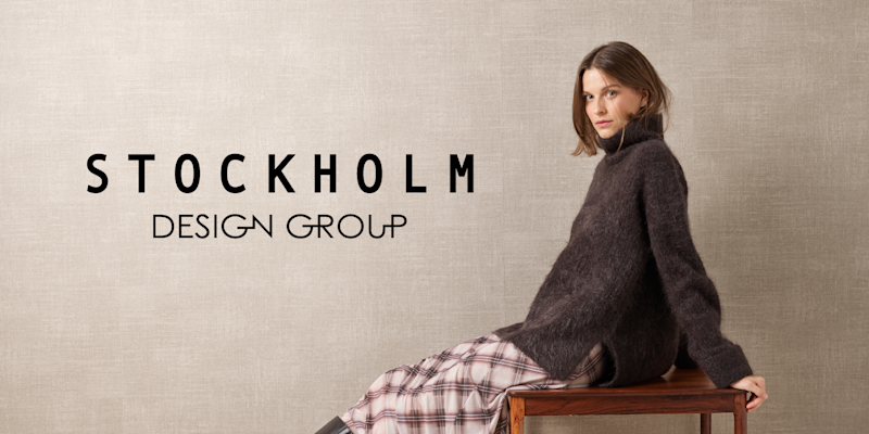 Person i mørk genser sitter på bord foran beige bakgrunn med "STOCKHOLM DESIGN GROUP" logo.